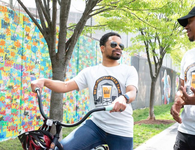 bikers enjoying the metropolitan beer trail in front of colorful mural
