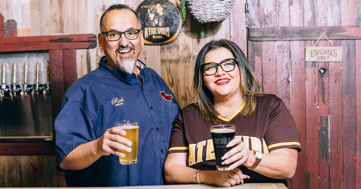 Atrevida founders holding beer behind brewery