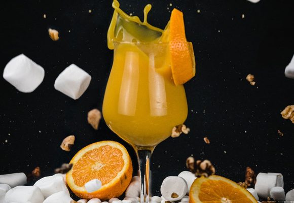 orange beer with marshmallows nuts and oranges flying in the background