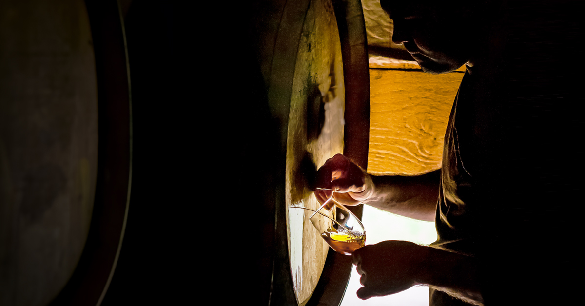 man collecting barrel aged beer from barrel
