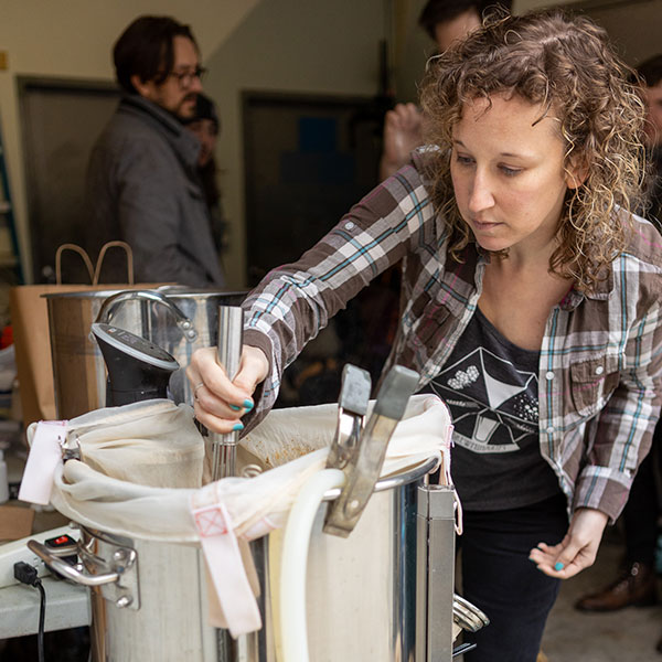 woman stirring brew kettle during homebrew process 