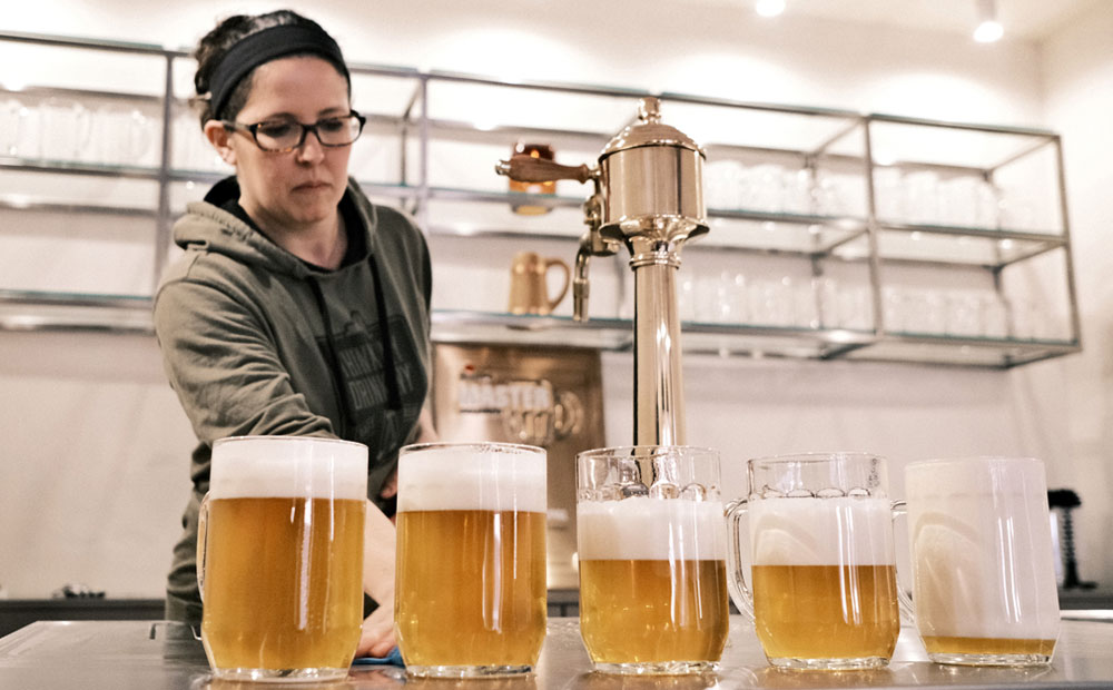 woman surveying pitchers of beer and foam