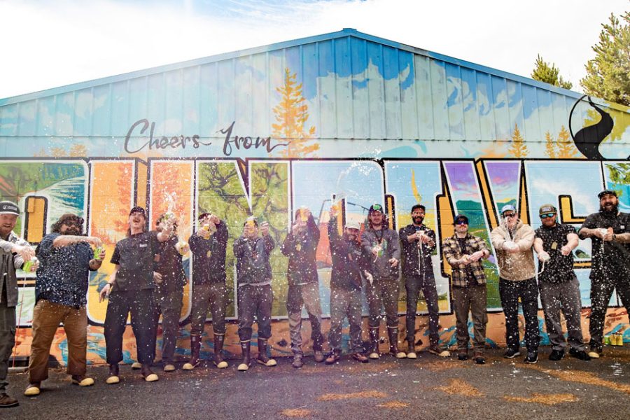 people spraying beverages outside sunriver mural